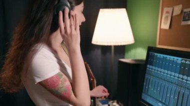 Ev kayıt stüdyosunda bayan müzisyen şarkısı. Gitar çalan ve sentezleyen genç bir kadın eşitleyici programı kullanarak müzik yaratıyor. Yaratıcılık sürecinden zevk alan kız.