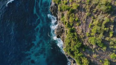 Gök mavisi deniz dalgaları, bol köpüklü kayalar ve ağaçlarla dolu inanılmaz tropikal doğa. Doğal güçlerin gösterimi. Seyahat kavramı. Deniz gelgitlerinin kayalıklara çarpması için muhteşem bir manzara..