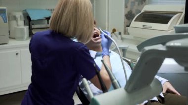 Diş aletlerini kullanarak ağız temizliği. Hasta dişçi muayenehanesinde ağzı açık yatıyor. Stomatolog muayene ediyor ve dişlerle ilgileniyor. Sağlıklı gülümseme kavramı