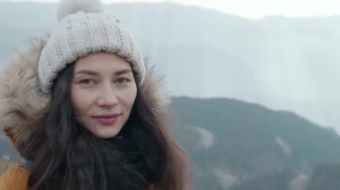 Dağ manzarasının dumanlı arka planında genç bir yürüyüşçü. Asyalı kadın turistin portresi soğuk havada bulutlu dağlarda temiz hava solumaktan hoşlanıyor. Etkin yaşam biçimi kavramı