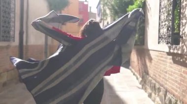 Çekici genç Asyalı kadın şık kırmızı bir kazak giymiş çizgili pançosunu sallıyor ve öpücük yolluyor. Küçük bir sokakta koşuşturan ve İtalya 'da maceralara hazır eğlenceli bir kız..