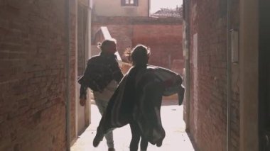 Balayı kavramı. Venedik 'te güneşin doğuşunda koşan romantik melez çift. İtalya 'daki antik şehrin dar sokaklarında gezip maceralar arayan mutlu genç aşıklar..