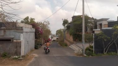 Bali, Endonezya - 30 Mart 2018: Küçük Afrika yerleşim alanındaki dar sokakları Axel Drone görüntüsü. İnsanlar renkli çalılarla çevrili konforlu evler arasında küçük yollarda scooter kullanıyor.