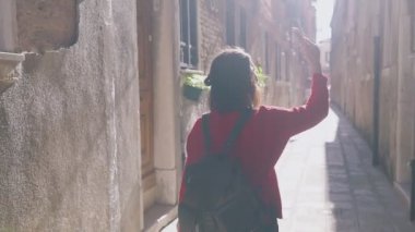 Maceracı Asyalı kadının Venedik, İtalya 'da akıllı telefonuyla küçük rahat caddelerin videosunu kaydettiği arka manzara. Kadın sırt çantası Instagram 'ı için ilginç materyaller hazırlıyor. Blogger hayatı