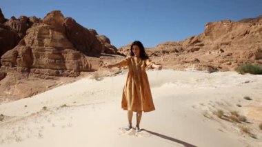 Genç gezgin, güneşli çöl kum tepeciğinde duruyor ve ellerinin önünde parçacıkları eliyor. Güzel bir kadın bir avuç kuru kumu alır ve parmaklarının arasına bırakır..