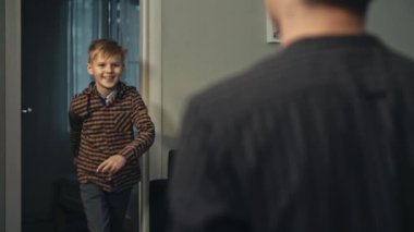 Genç baba sonunda işten eve geliyor. Gülümseyen oğul, akşam babasını kapıda karşılıyor. Mutluluk kavramı. Babasına koşan ve ona sarılan sıradan giysili mutlu genç oğlanın yakın çekimi..