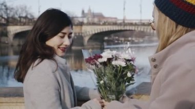 Yakın arkadaşlar nehir kenarında buluşur ve kameranın önünde çiçek buketi değiş tokuşu yapar, birbirlerine sarılırlar. Homoseksüel aile romantik zaman geçiriyor. Lgbt ilişki kavramı.