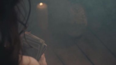 Gizemli ayine hazırlanan tarot kartları karıştıran bir kadın. Falcı, Odrer 'e gizli kehanet ayini için kart koyuyor. Gizem ve Cadılar Bayramı atmosferi mum ve dumanla güçlendirilir..