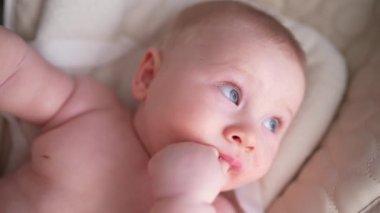 Pencerenin yanında beyaz bir sandalyede oturan sevimli yeni doğmuş erkek bebek. Mutlu, melez bir ailenin neşeli yaşam tarzı. Genç Asyalı bir kadın ve aktif, sağlıklı, tavşan kostümlü mavi gözlü bir bebek.