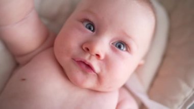 Pencerenin yanında beyaz bir sandalyede oturan sevimli yeni doğmuş erkek bebek. Mutlu, melez bir ailenin neşeli yaşam tarzı. Genç Asyalı bir kadın ve aktif, sağlıklı, tavşan kostümlü mavi gözlü bir bebek.