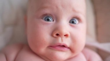 Pencerenin yanında beyaz bir sandalyede oturan sevimli yeni doğmuş erkek bebek. Mutlu, melez bir ailenin neşeli yaşam tarzı. Genç Asyalı bir kadın ve aktif, sağlıklı, tavşan kostümlü mavi gözlü bir bebek.