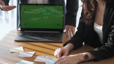 İş arkadaşlarının masa başında yaklaşan projeleri tartıştığı bir ofis sahnesi. Meslektaşlar dizüstü bilgisayardaki sunum planı hakkında fikir alışverişinde bulunuyorlar. Takım çalışması kavramı, teknoloji.