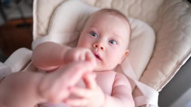 Pencerenin yanında beyaz bir sandalyede oturan sevimli yeni doğmuş erkek bebek. Mutlu, melez bir ailenin neşeli yaşam tarzı. Genç Asyalı bir kadın ve aktif, sağlıklı, tavşan kostümlü mavi gözlü bir bebek.