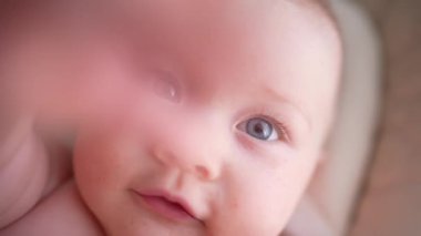 Pencerenin yanında beyaz bir sandalyede oturan sevimli yeni doğmuş erkek bebek. Mutlu, melez bir ailenin neşeli yaşam tarzı. Genç Asyalı bir kadın ve aktif, sağlıklı, tavşan kostümlü mavi gözlü bir bebek.