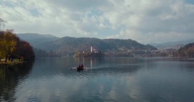 Yaz tatili izolasyonu. Puslu günbatımında Bled Gölü 'nde teknede oturan şapkalı romantik kadın. Seyahat macerası sırasında rahatlayan bir kızın arka görüntüsü. Özgürlük, deneyim, gezi konsepti.