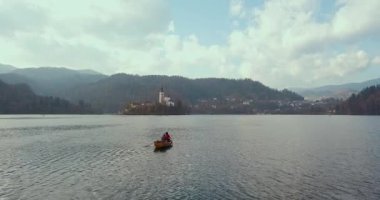 Yaz tatili izolasyonu. Puslu günbatımında Bled Gölü 'nde teknede oturan şapkalı romantik kadın. Seyahat macerası sırasında rahatlayan bir kızın arka görüntüsü. Özgürlük, deneyim, gezi konsepti.