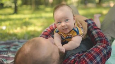 Babamızın üstünde kasaba parkında yerde yatan bir bebek. Gülümseyen çocuk, ailesi dışarıda güneşli bir gün yaşıyor. Bir çocuğa sevgi ve ilgi gösteren bir ebeveyn. Aile kavramı, birlikte..