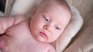 Pencerenin yanında beyaz bir sandalyede oturan sevimli yeni doğmuş erkek bebek. Mutlu, melez bir ailenin neşeli yaşam tarzı. Genç Asyalı bir kadın ve aktif, sağlıklı, tavşan kostümlü mavi gözlü bir bebek.