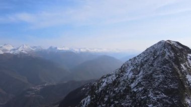 Sisli, güneşli bir günde beyaz karlı zirvelerde insansız hava aracının muhteşem görüntüsü. Yukarıdan karla kaplı dağ sırasının havadan görüntüsü. Seyahat kavramı, ilham verici, doğa, kış.