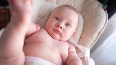 Pencerenin yanında beyaz bir sandalyede oturan sevimli yeni doğmuş erkek bebek. Mutlu, melez bir ailenin neşeli yaşam tarzı. Genç Asyalı bir kadın ve aktif, sağlıklı, tavşan kostümlü mavi gözlü bir bebek.