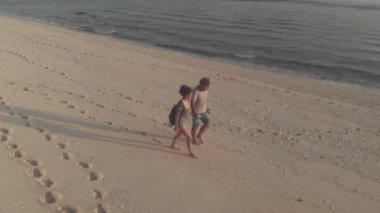 Romantik çiftin hava aracı görüntüsü gün batımının arka planında birbirlerine bakıyor. Aşık bir çift okyanus boyunca yürüyor. Aşıklar öpüşür, romantik yolculukta el ele tutuşur..