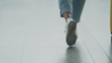 Kayıt standına doğru ilerleyen genç iş kadınının arkasından bir görüntü. Genç bir kadın havaalanı terminalinde bavuluyla yavaşça yürüyor. Kız iş gezisine hazırlanıyor. Seyahat kavramı.