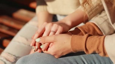 Değer veren genç bir kadın arkadaşını destekliyor ve empati ve destek veriyor. Dışarıda oturan iki kız arkadaşın kadın ellerine yakın durun..