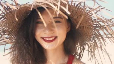 Hasır şapkalı neşeli Asyalı kadın parmaklarının arasındaki kumu elliyor. Kırmızı elbiseli güzel bayan cennet adasının tadını çıkarıyor, güneş parlıyor. Romantik ve sakin bir ruh hali. Bali 'nin seyahat tarzı.