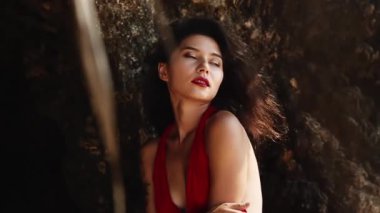 Kırmızı elbiseli, melez bir kadın. Lüks, şehvetli Asyalı kız portresi kameraya gülümsüyor. Sıcak yaz günü, tropik cennet adasında kalırken seksi pozlar. Ticari, müstehcen yaşam tarzı