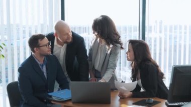 Bir grup genç ofis çalışanı yaklaşan sunum stratejisini tartışıyor. Takım toplantısı sırasında iş arkadaşları beyin fırtınası yapıyor. Takım oluşturma kavramı.