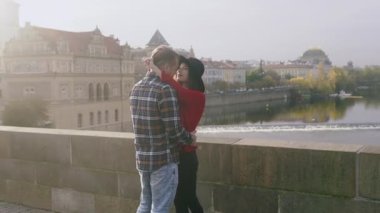 Genç aşıklar öpüşüyor ve birlikte vakit geçiriyorlar. Tatlı çiftin, eski Avrupa kasabasında, günbatımı köprüsünde romantik bir randevusu var..