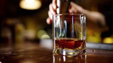 Profesyonel bir barmen, barda veya disko kulübünde müşterilere buz küplü alkollü bir kokteyl hazırlıyor. Profesyonel bir barmene yakın plan alkollü kokteylle profesyoneli karıştırmaktır.