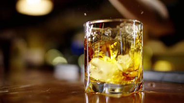 Profesyonel bir barmen, barda veya disko kulübünde müşterilere buz küplü alkollü bir kokteyl hazırlıyor. Profesyonel bir barmene yakın plan alkollü kokteylle profesyoneli karıştırmaktır.