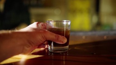 Alkol çubuğunun boyunca sürgülü cam counter, ağır çekim. El kadar bir içki alır.