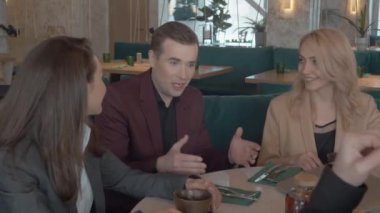 Takım elbiseli bir grup iş arkadaşı kafede dizüstü bilgisayarla çalışma durumunu tartışıyor. Gündelik iş arkadaşları restoranda pırıl pırıl sohbet ediyorlar. Takım oluşturma, boş zaman kavramı.