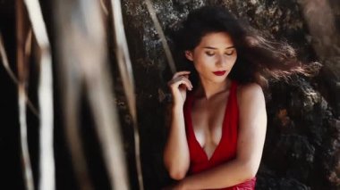 Sıcak yaz günü. Lüks, şehvetli Asyalı kız portresi kameraya gülümsüyor. Kırmızı elbiseli, melez bir kadın. Tropik cennet adasında kalırken seksi poz vermek. Ticari, müstehcen yaşam tarzı