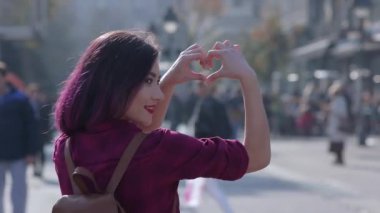 Kalp şeklini elleriyle gösteren kadın. Güzel bir Asyalı kız yazı Avrupa 'da tatilde geçirir. Kız mutlu ve hayattan zevk alıyor. Bir kadın Avrupa sokaklarında yürüyor. Arkadaşlık ve aşk