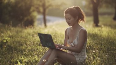 IT uzmanı dışarıda kendini izole ediyor. Kız parkta ya da ormanda oturuyor, doğada dizüstü bilgisayar açıyor. İş yapan ya da doğada serbest çalışan ya da inanılmaz güneş ışığında temiz hava alan bir kadın..