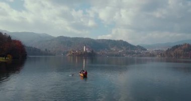 Yaz tatili izolasyonu. Puslu günbatımında Bled Gölü 'nde teknede oturan şapkalı romantik kadın. Seyahat macerası sırasında rahatlayan bir kızın arka görüntüsü. Özgürlük, deneyim, gezi konsepti.