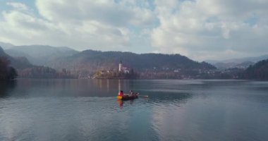 Yaz tatili izolasyonu. Puslu günbatımında Bled Gölü 'nde teknede oturan şapkalı romantik kadın. Seyahat macerası sırasında rahatlayan bir kızın arka görüntüsü. Özgürlük, deneyim, gezi konsepti.