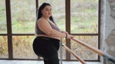 Şişman kadın izole edilmiş egzersizler yapıyor. Rasta saçlı mutlu vücutlu şişman kadın spor salonunda esneme hareketleri yapıyor. Doğal güzellik ve spor anlayışı. Rahatlama sükunet konsepti