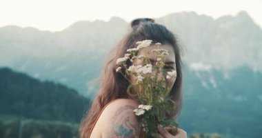 Dağın tepesinde çiçekleri olan tatlı Asyalı genç bir kadın. Yaz doğa manzarası. Kız turist deniz kenarında uçurumun kenarında duruyor. Sinema havası, yumuşak tonlar, dağlık çayırlar ve...