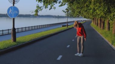 Güzel sarışın koşmadan ya da egzersiz yapmadan önce ısınıyor. Kız rıhtım boyunca koşmadan önce kol ve bacak kaslarını esnetiyor. Karantinada aktif ve sağlıklı bir yaşam tarzı sürdüren atletik kadın.