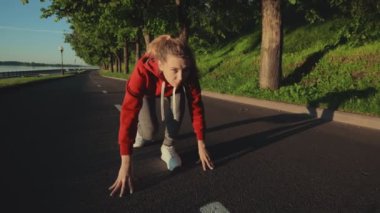 Atletik kızın portresinin yakın plan çekimi düşük seviyeden başlıyor. Fiziksel olarak iyi durumda olan bir kadın şehirde nehir kıyısı boyunca koşuyor. İzolasyon sırasında spor ve spor.