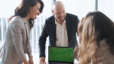 İş arkadaşlarının masa başında yaklaşan projeleri tartıştığı bir ofis sahnesi. Meslektaşlar dizüstü bilgisayardaki sunum planı hakkında fikir alışverişinde bulunuyorlar. Takım çalışması kavramı, teknoloji.