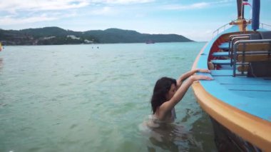 Kadın uzun kuyruklu tekneye atlıyor. Tayland 'da turizm ve eğlence. Yakışıklı Asyalı kadın adaları geziyor. Kız hayattan zevk alıyor ve eğleniyor. Cennet kumsalları ve beyaz kum