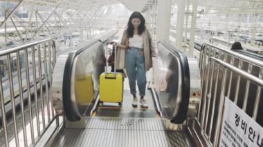 Güzel bir kadın iş seyahatinde trende çalışıyor. Genç iş kadını tren istasyonunda bavuluyla yürüyen merdivene biniyor. Platforma çıkan parlak merdivenler. Seyahat kavramı.
