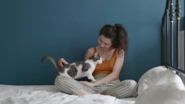 Sevimli evcil hayvan konsepti. Genç ve güzel Asyalı kadın sabah yatak odasında güzel kedisiyle oynuyordu. Kız ve küçük komik kediciği birlikte.