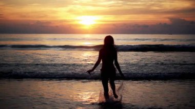 Gün batımında denizde koşan kadın silueti. Tayland 'da turizm ve eğlence. Yakışıklı Asyalı kadın adaları geziyor. Kız hayattan zevk alıyor ve eğleniyor. Cennet kumsalları ve beyaz