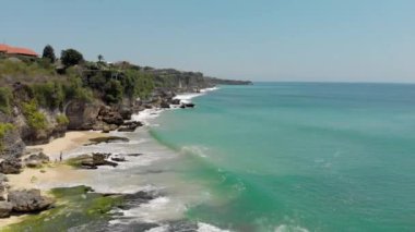 Alex egzotik deniz manzarasının insansız hava aracı görüntüsü. Kayalık kayalıklardaki güzel hortumlar mavi denizle buluşan ağaçlarla çevrili. Küçük deniz dalgaları, insansız hava aracıyla kayalık kıyılarda kırılıyor. Seyahat kavramı.